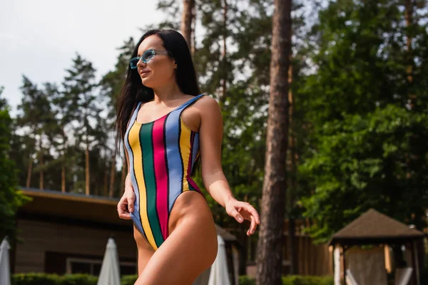 Low angle view of brunette woman in swimwear standing outdoors — Stock Photo