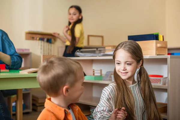 Niños hablando en aula cerca maestro y asiático chica en borrosa fondo - foto de stock