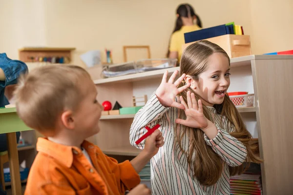 Menina mostrando parar gesto perto menino assustando-a com elemento de quebra-cabeça — Fotografia de Stock