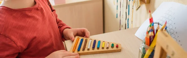 Recortado vista de niño jugando con cuentas de colores juego en la escuela montessori, bandera — Stock Photo