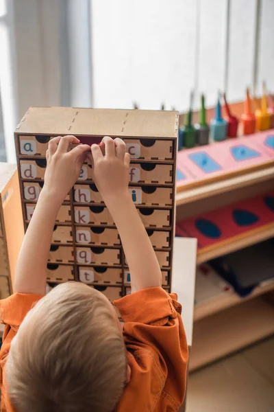Vue arrière de l'alphabet d'apprentissage des garçons tout en jouant à un jeu éducatif à l'école montessori — Photo de stock