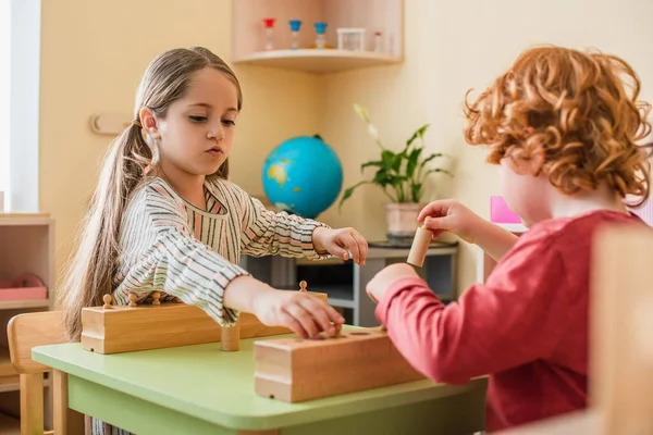 Offuscata rossa ragazzo giocare cognitivo gioco con ragazza in montessori scuola — Foto stock