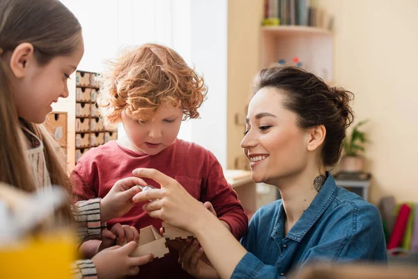 Insegnante sorridente giocare gioco educativo con i bambini nella scuola montessori — Foto stock