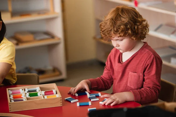 Lockenkopf sortiert bunte Karten bei Mädchen in Montessori-Schule — Stockfoto