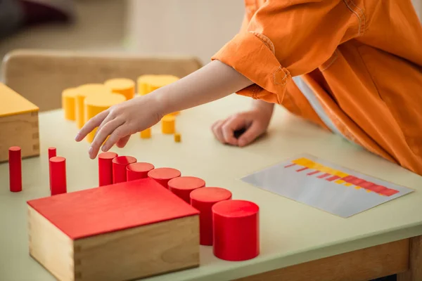 Ausgeschnittene Ansicht eines Jungen, der in der Montessori-Schule mit roten und gelben Zylindern spielt — Stockfoto