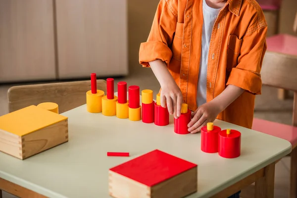 Vista cortada do menino combinando blocos vermelhos e amarelos na escola montessori — Fotografia de Stock