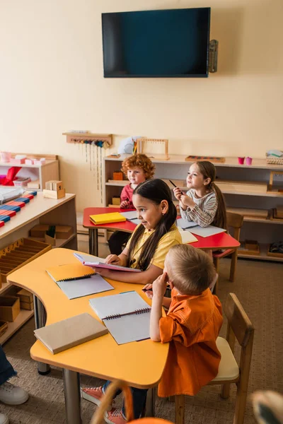 High angle view of asian girl reading book near children during lesson — Stock Photo