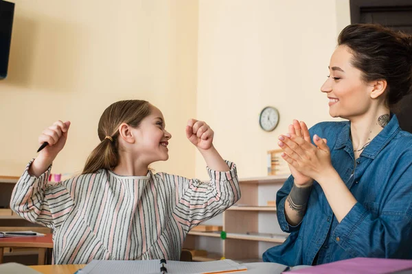 Happy teacher applauding near excited kid showing win gesture in montessori school — Stock Photo