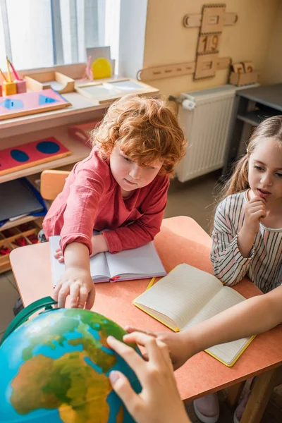 Bambini che guardano il globo durante le lezioni nella scuola montessori — Foto stock