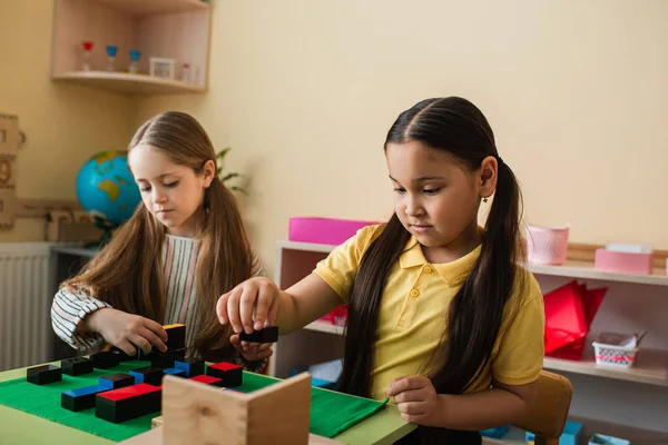 Interracial girls playing educational game in montessori school — Stock Photo