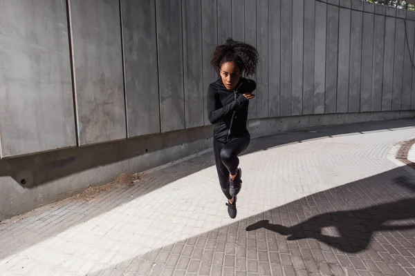 African american sportswoman looking at camera while running on urban street — Stock Photo