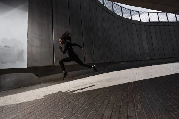 Vue latérale d'un coureur afro-américain travaillant dans une rue urbaine — Photo de stock