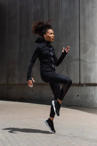 Side view of pretty african american sportswoman training on urban street — Stock Photo