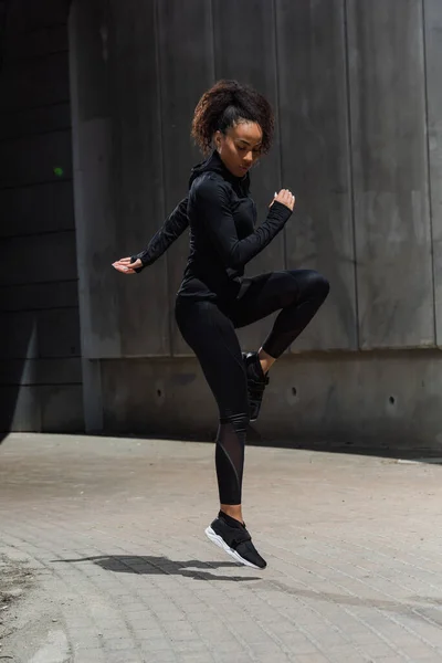 Femme afro-américaine sautant tout en faisant de l'exercice dans la rue urbaine — Photo de stock