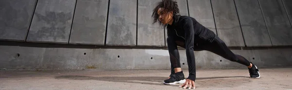 Young african american runner standing in starting pose on urban street, outdoors — Stock Photo