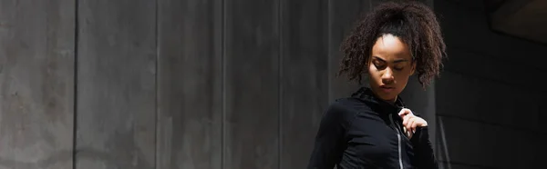 Joven deportista afroamericana de pie a la luz del sol al aire libre, pancarta - foto de stock