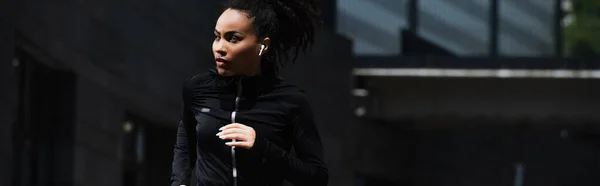 Femme afro-américaine dans le jogging de l'écouteur à l'extérieur, bannière — Photo de stock