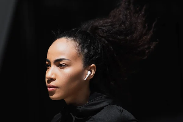Young african american sportswoman in wireless earphone outdoors — Stock Photo