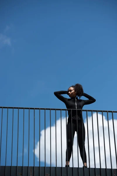 Visão de baixo ângulo da esportista afro-americana em pé na ponte — Fotografia de Stock