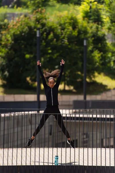 Afroamericana deportista saltando mientras entrena en puente - foto de stock