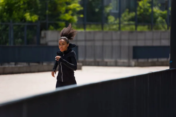 Подходящая африканская американская спортсменка, бегающая на свежем воздухе днем — стоковое фото