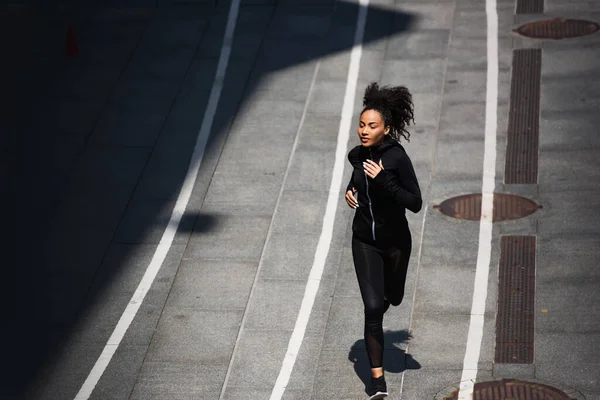 Vista ad alto angolo della giovane sportiva afroamericana che fa jogging sulla pista da corsa — Foto stock