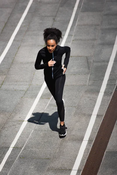 Vista de alto ángulo del entrenamiento de corredores afroamericanos en pista al aire libre - foto de stock