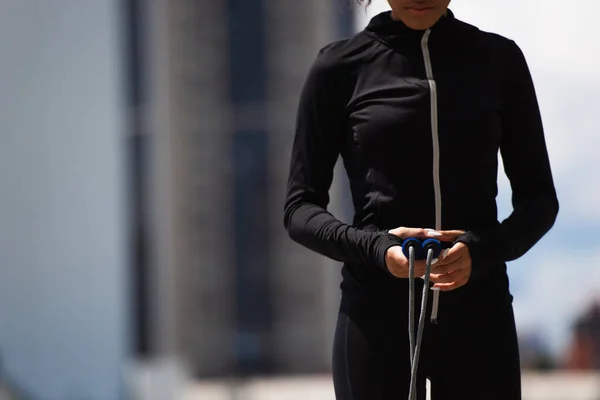 Vue recadrée d'une sportive afro-américaine tenant une corde à sauter à l'extérieur — Photo de stock