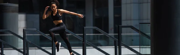 Fit african american runner near railing on urban street, banner — Stock Photo