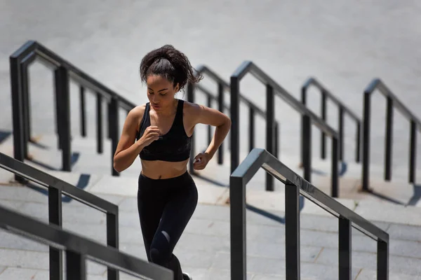 African american woman running on stairs near blurred railing — Stock Photo