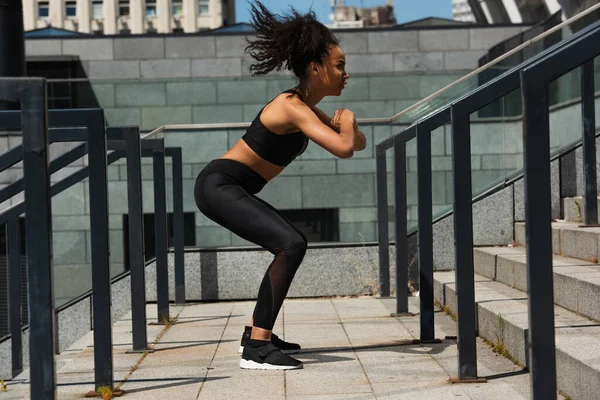 Side view of african american sportswoman trailing on stairs outdoors — Stock Photo