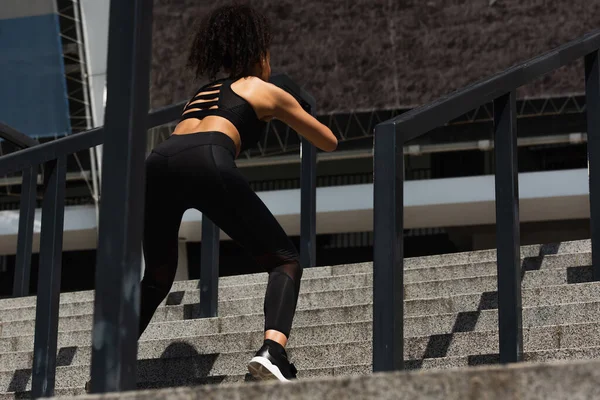 Back view of african american woman exercising on stairs near railing — Stock Photo