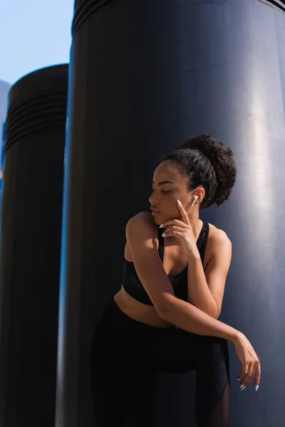 Femme sportive afro-américaine dans un écouteur et haut debout à l'extérieur — Photo de stock