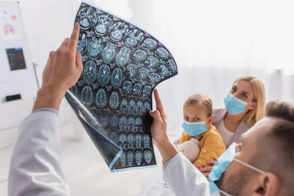 Pediatra desfocado segurando ressonância magnética perto de mãe e filho em máscaras médicas — Fotografia de Stock