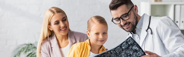 Lächelnder Kinderarzt mit einem MRI-Scan in der Nähe von Patient und Eltern in der Klinik, Banner — Stockfoto