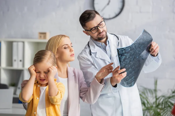 Krankes Kind mit Kopfschmerzen nahe der Mutter zeigt auf Mammografie und Kinderarzt — Stockfoto
