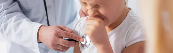 Niño estornudando cerca del médico con estetoscopio, pancarta - foto de stock