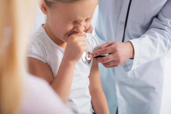 Pediatrician using stethoscope near diseased child in hospital — Stock Photo