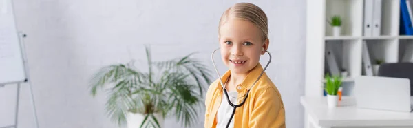 Positives Kind im Stethoskop blickt in Klinik in die Kamera, Banner — Stockfoto