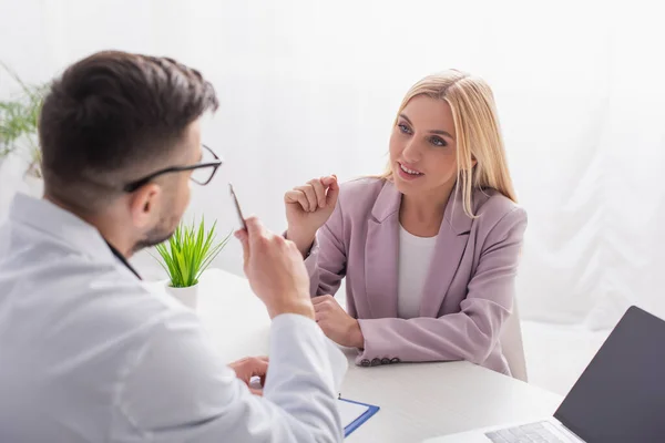 Lächelnde Frau im Gespräch mit Arzt während eines Krankenhausaufenthalts — Stockfoto