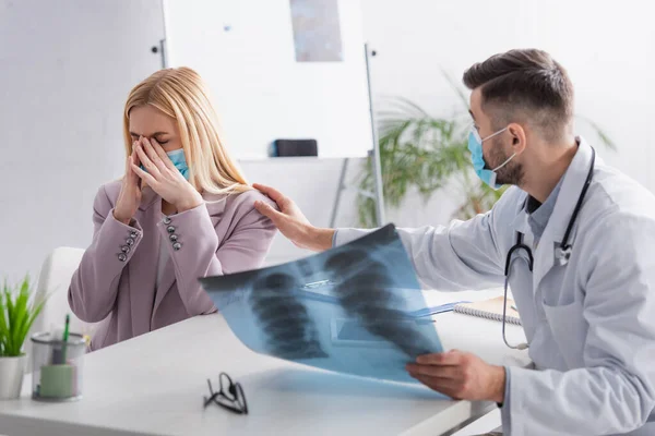 Medico con i polmoni radiografia calmante donna sconvolta piangendo in maschera medica — Foto stock