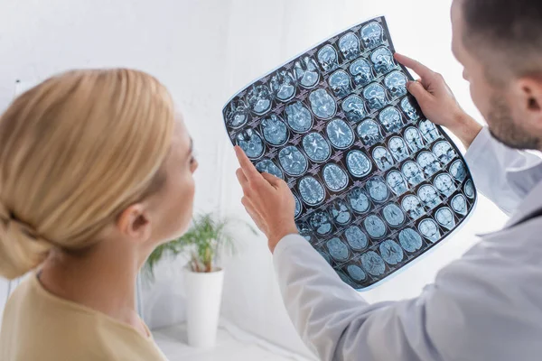 Physician showing mri scan to patient in clinic on blurred foreground — Stock Photo