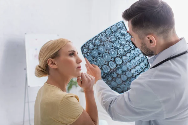 Médico mostrando ressonância magnética para a mulher durante a consulta — Fotografia de Stock