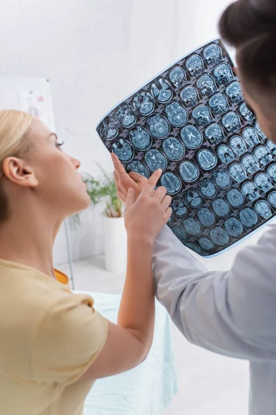 Femme pointant vers le cerveau IRM scanner entendre médecin à l'hôpital — Photo de stock
