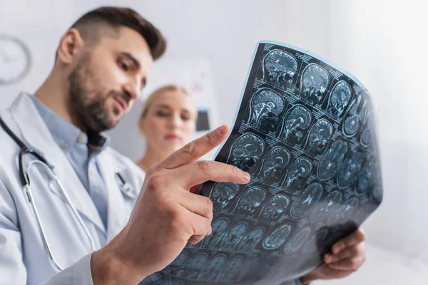 Blurred doctor and patient looking at brain mri scan in hospital — Stock Photo