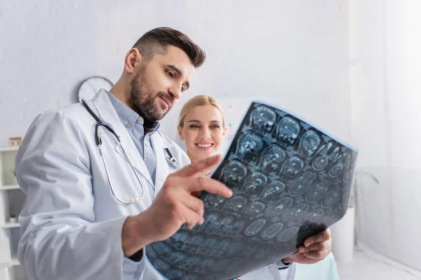 Femme heureuse regardant le scanner du cerveau IRM dans les mains du médecin — Photo de stock