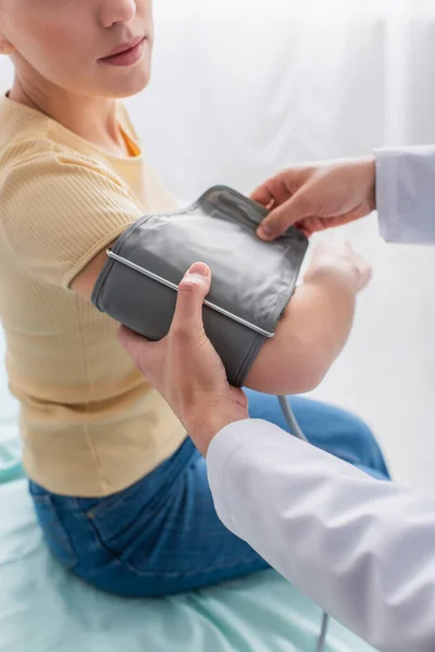 Partial view of doctor putting cuff of tonometer on arm of patient — Stock Photo