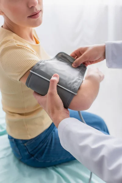 Vista parziale del medico che mette il bracciale del tonometro sul braccio del paziente — Foto stock