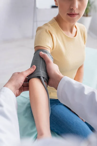 Teilansicht eines verschwommenen Arztes, der Frau Manschette mit Tonometer anlegt — Stockfoto