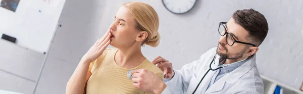 Mujer tosiendo mientras el médico la examina con estetoscopio, pancarta - foto de stock